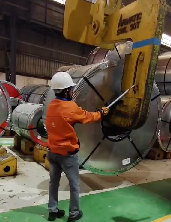 Operator positioning a tool against a coil lifting attachment