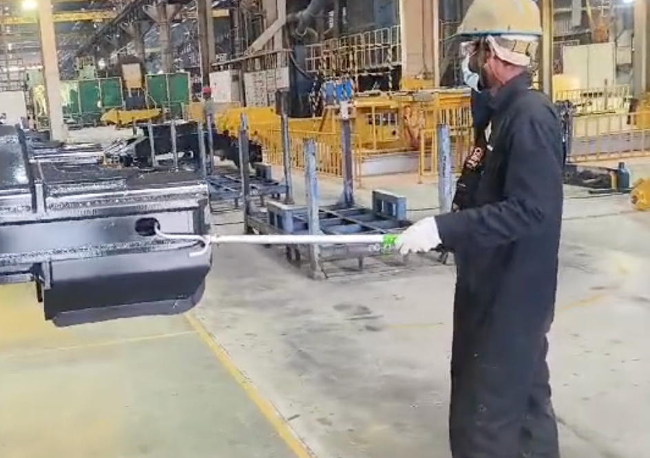 Operator using a hooked tool to guide a suspended industrial component