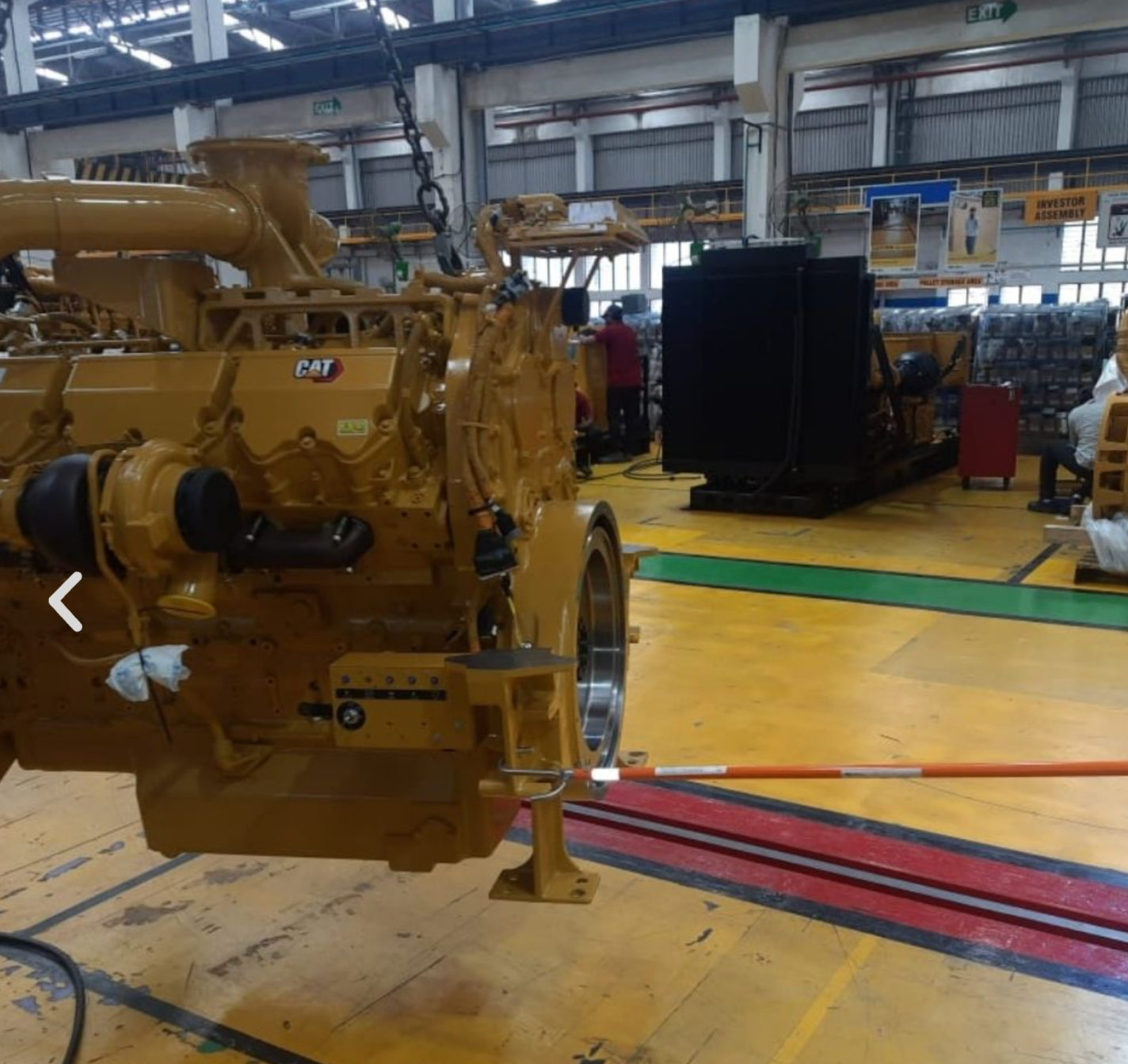 Hook tool engaging a large machinery component in an assembly workshop